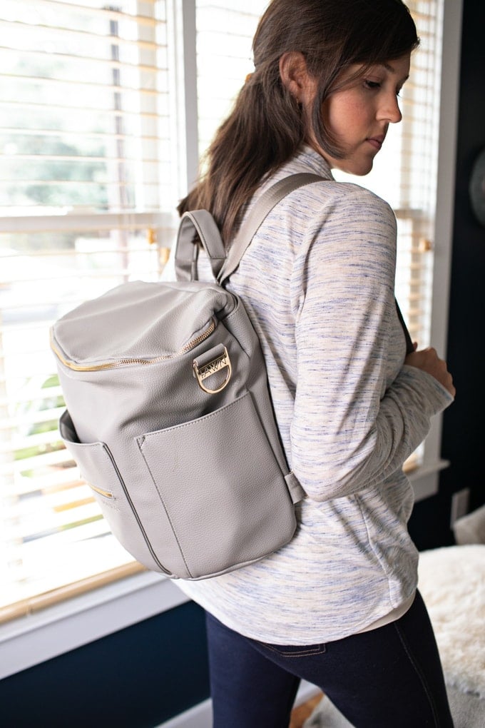 A grey backpack on the back of a woman.