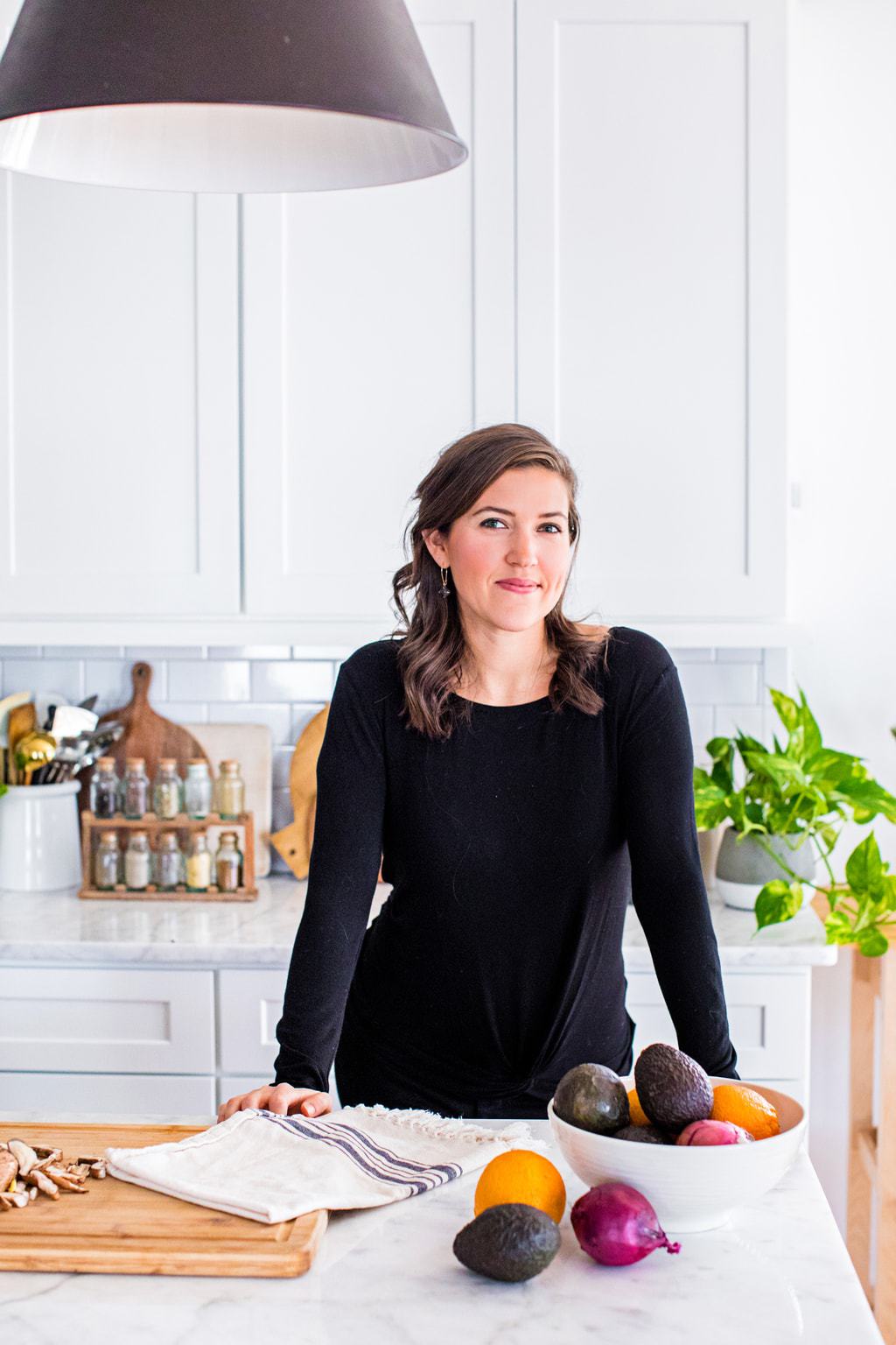 Kate Kordsmeier, a woman wearing black in a white kitchen.