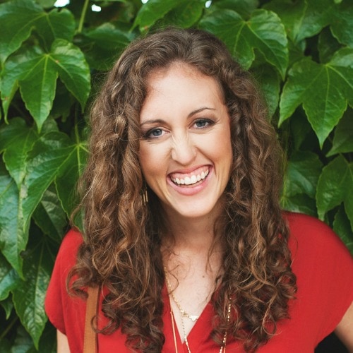 Laura Sprinkle headshot, a woman in a red shirt with long curly brown hair.