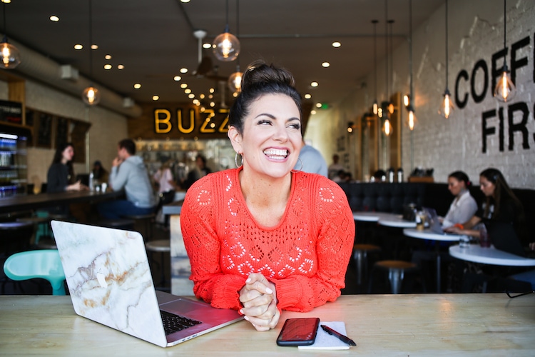 Amy Porterfield, a woman in a red sweater smiling in a coffee shop