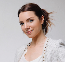 Brunette woman with hair pulled back, smiling at the camera with neutral background