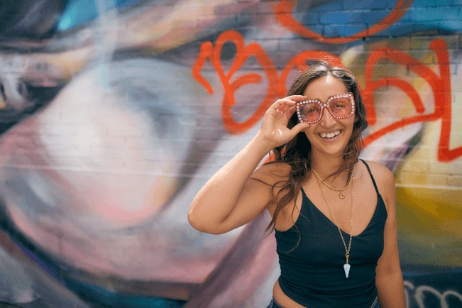 Young woman with sparkly sunglasses smiling at camera